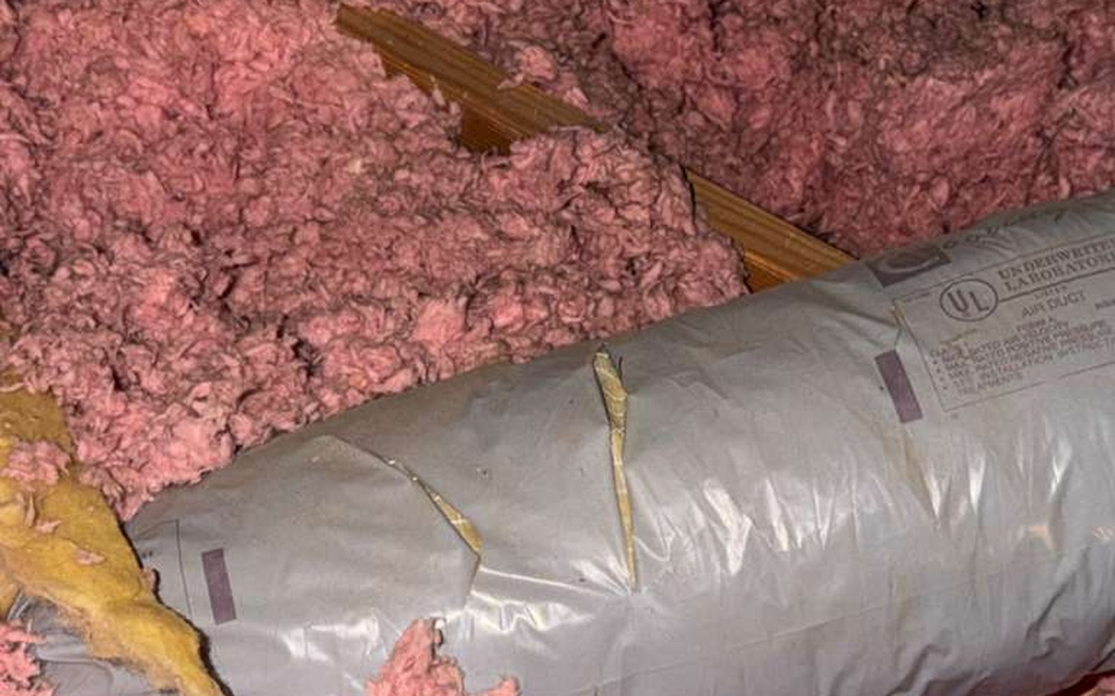 Failed UL-listed flex duct discovered in California home attic by California Airduct Pros — damaged outer jacket, exposed fiberglass insulation, and torn liner requiring full air duct replacement service