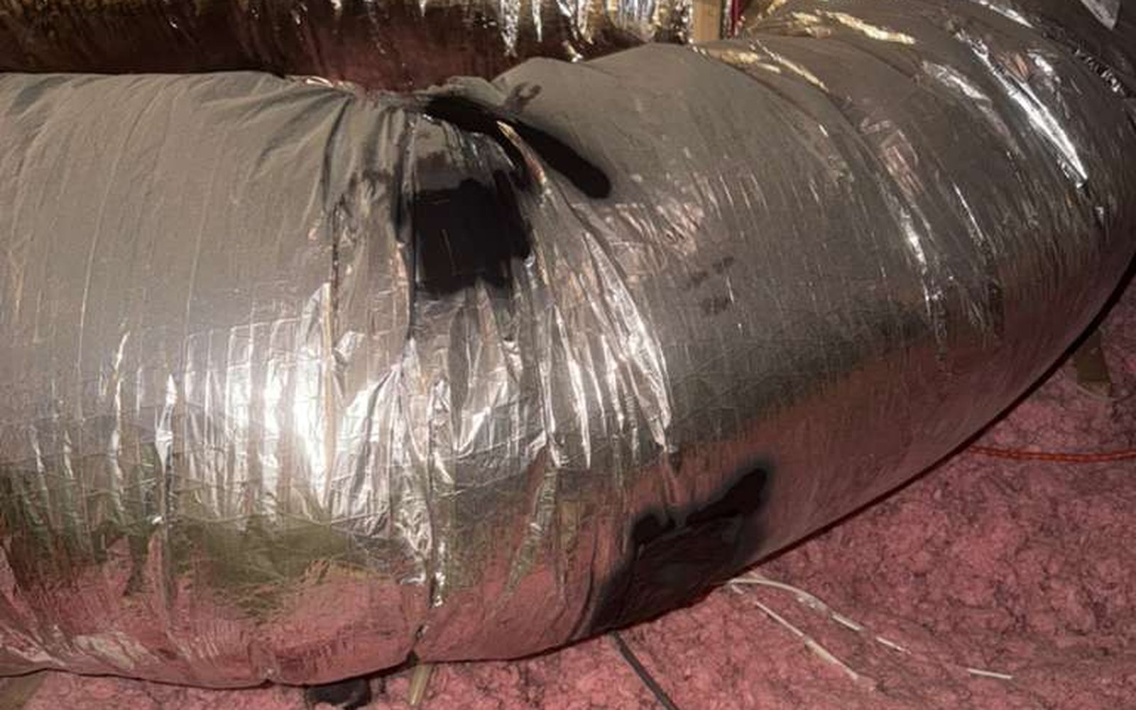 Severely damaged old air duct in California attic — crushed flex duct sections, torn outer jacket, and air leaks documented by California Airduct Pros before sealed removal and full duct replacement
