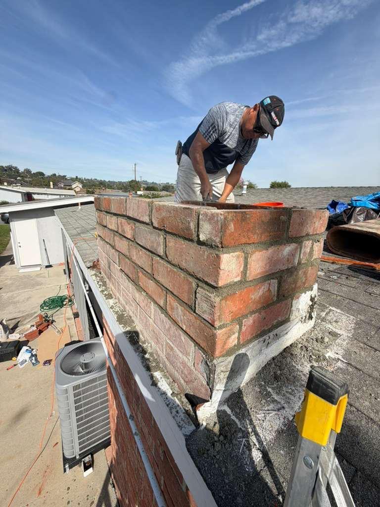 Technician performing professional chimney cleaning service on residential home in California